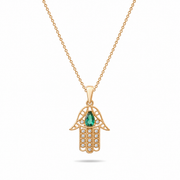 Gold Hamsa hand pendant with a green gemstone on a white background