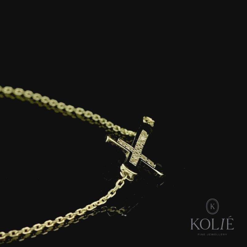 Sleek Kolié 9ct yellow gold bracelet featuring a horizontal cross, a modern twist on a classic design, set against a stark white background. View this piece and more at www.kolie.co.uk.
