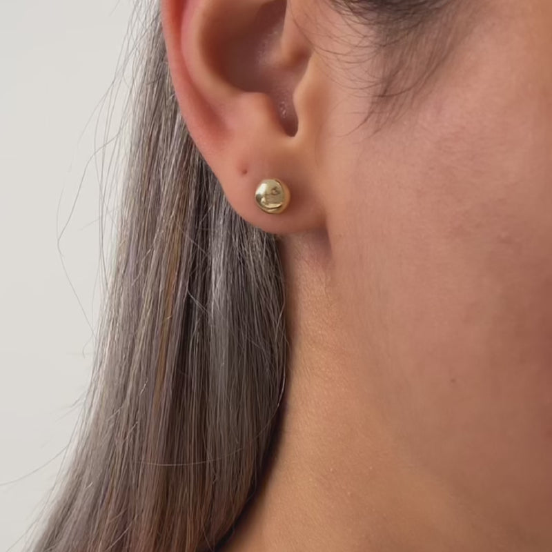 Close-up of an ear wearing a gold earring 