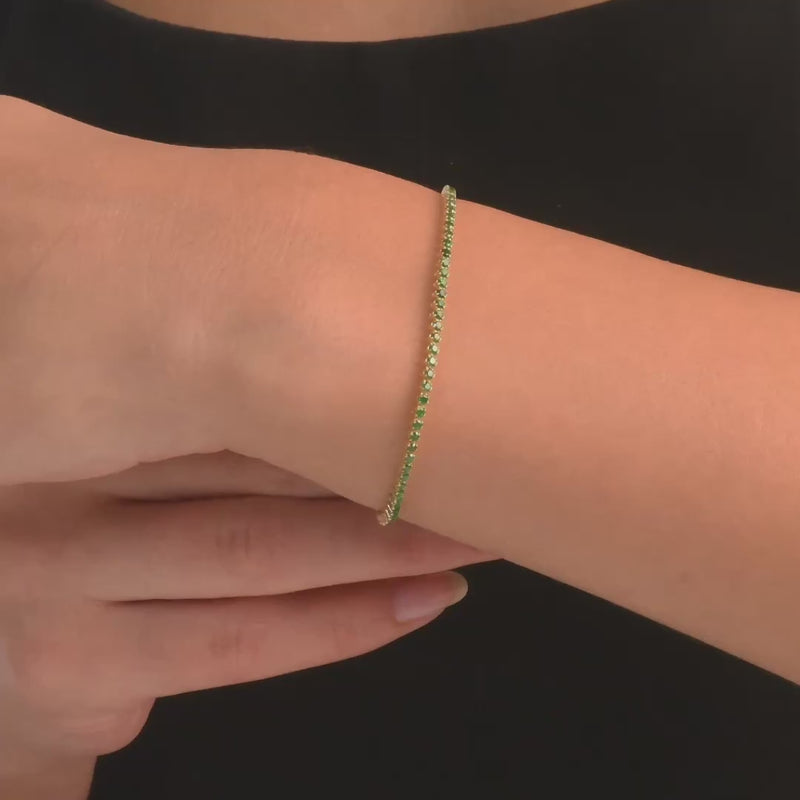 Woman wearing the 14ct gold green cubic zirconia bracelet, showing its vibrant sparkle on the wrist.