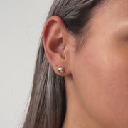 Gold round stud earrings worn by a model