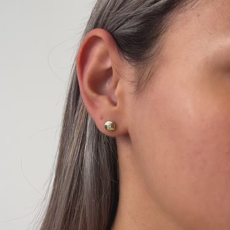 Gold round stud earrings worn by a model