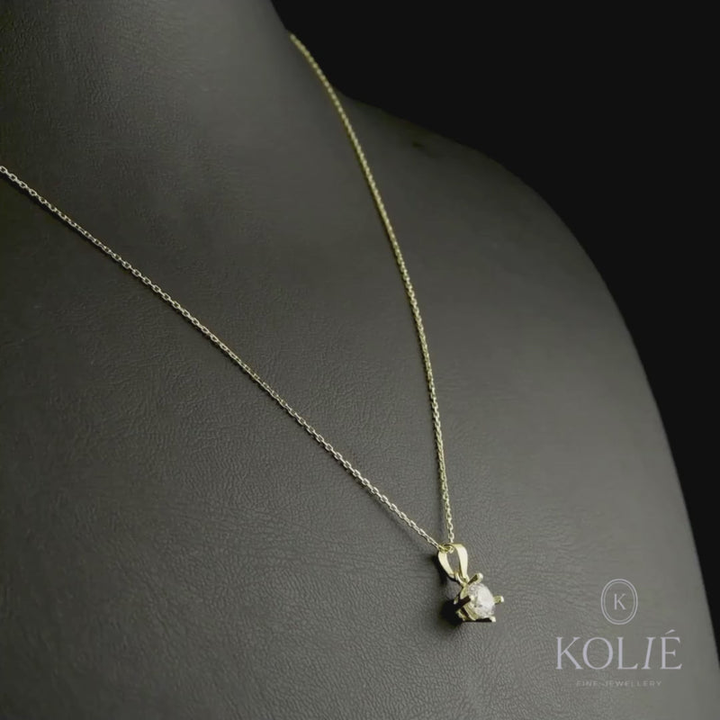 A detailed shot of the pendant with a chain, showcasing the sparkling cubic zirconia set in polished yellow gold.