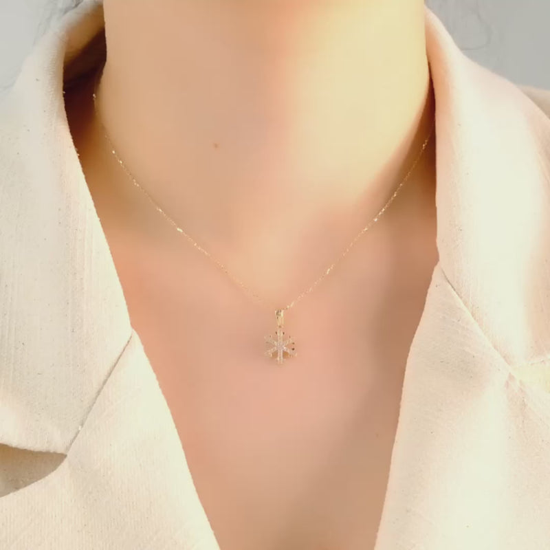 Video of gold snowflake pendant worn on a model, capturing the winter and holiday spirit.