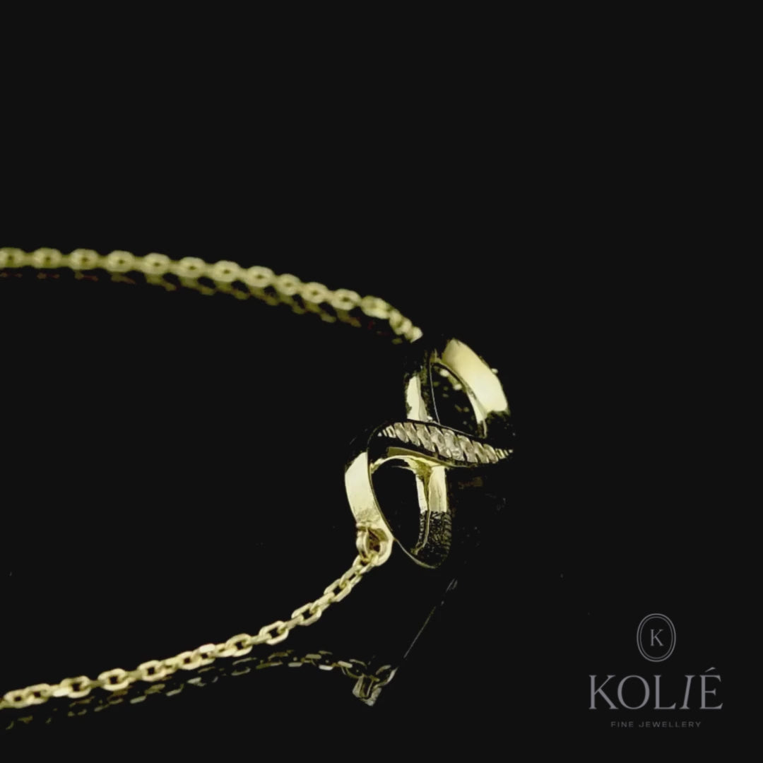 Dazzling Kolié 9ct yellow gold infinity bracelet, gracefully adorned with cubic zirconia, symbolizing eternal love, displayed on a black surface. Shop this timeless piece at www.kolie.co.uk.