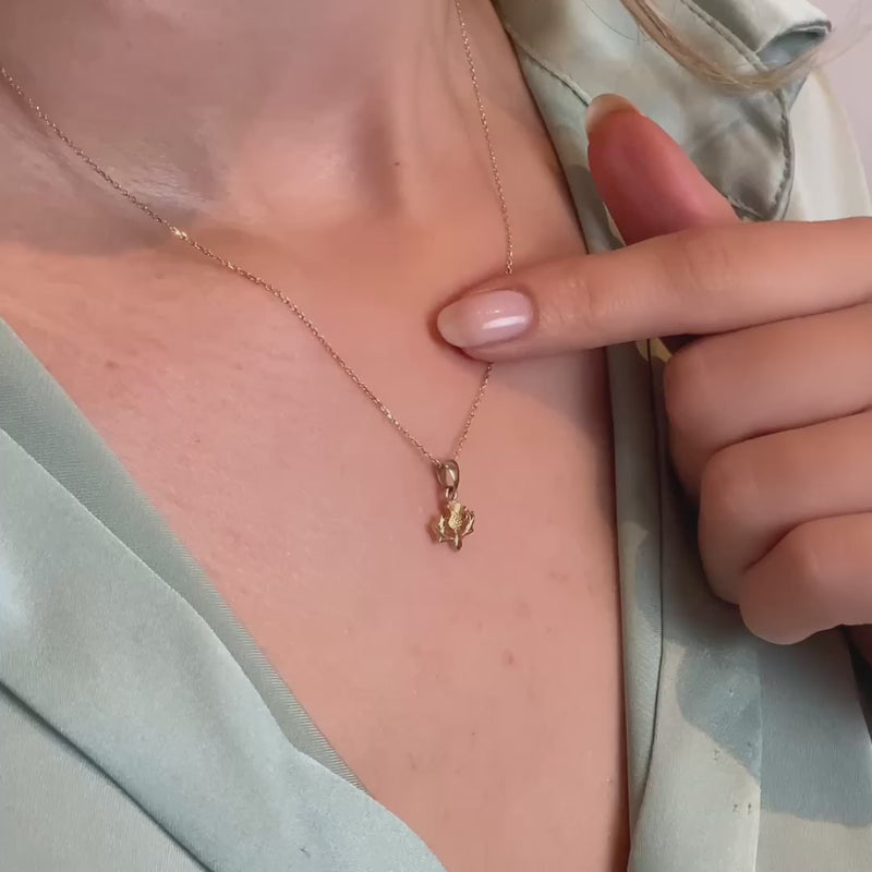 Video of a model wearing the gold thistle pendant, showcasing its delicate size and elegant design.
