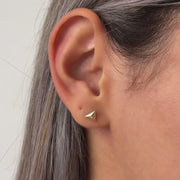 Close-up video of an ear wearing a gold triangle earring with a blurred background