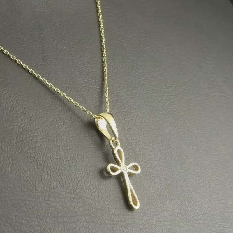 Cross pendant displayed on a black background, with the chain