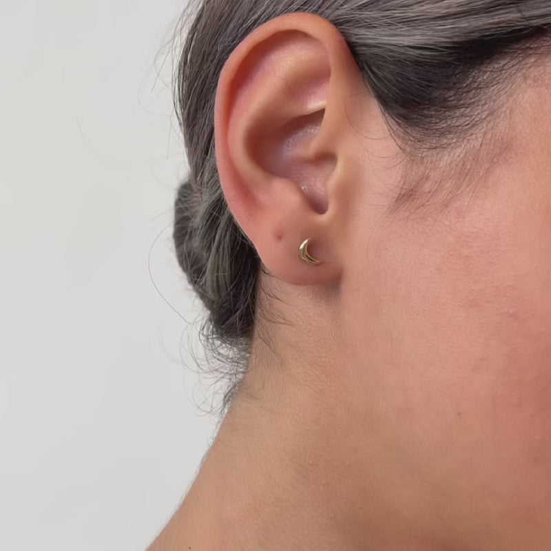 Close-up video of an ear wearing a gold moon-shaped earring 