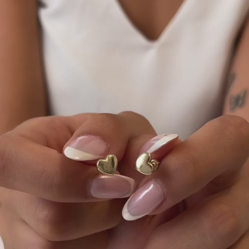 Close-up video of a gold heart-shaped earring with a blurred background