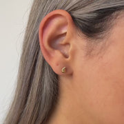 Close-up video f a person wearing a gold heart-shaped earring.