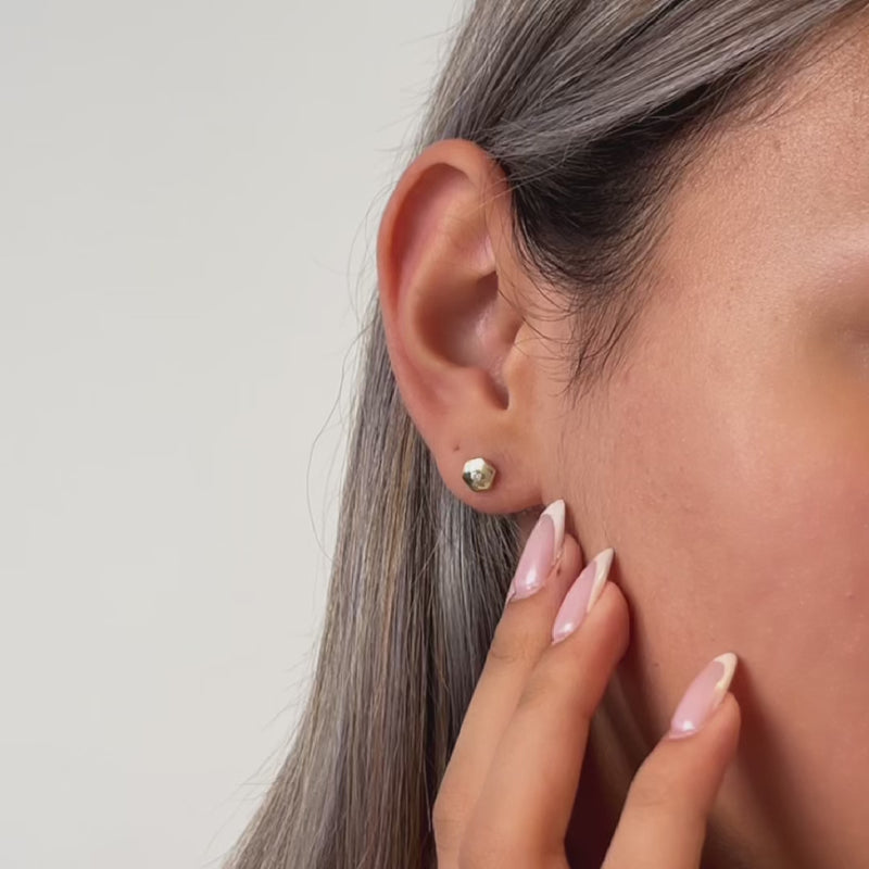 Gold hexagon stud earrings worn by a model