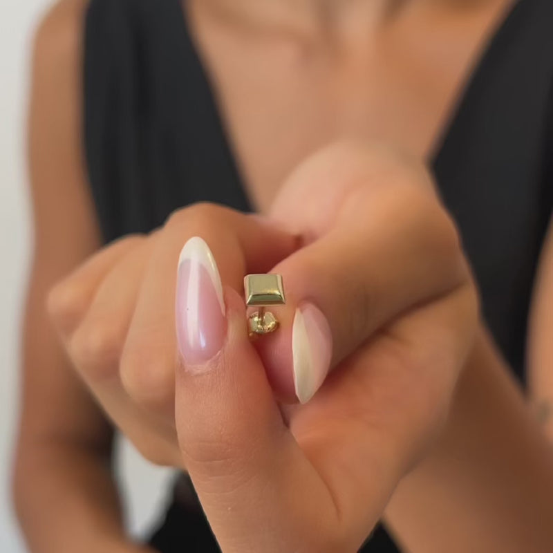 Close-up of a hand kept gold stud earring
